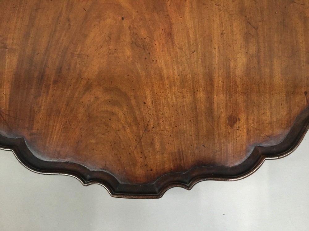 A mahogany George III style tripod table featuring a scalloped piecrust top, turned pedestal column, and cabriole legs with carved feet. View XI