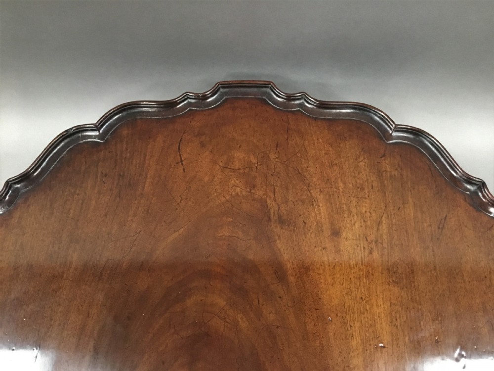 A mahogany George III style tripod table featuring a scalloped piecrust top, turned pedestal column, and cabriole legs with carved feet. View XII