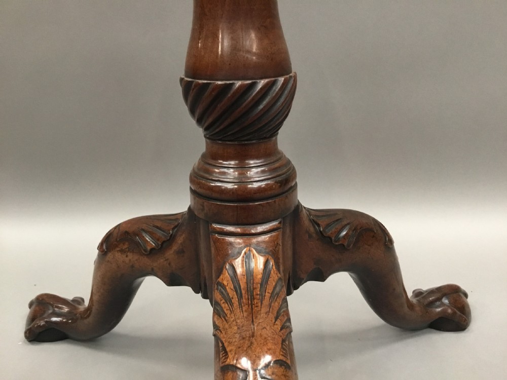 A mahogany George III style tripod table featuring a scalloped piecrust top, turned pedestal column, and cabriole legs with carved feet. View XVI