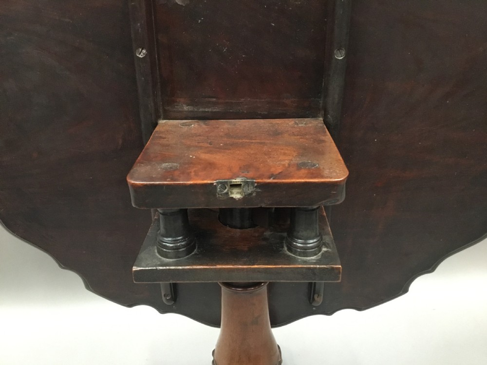 A mahogany George III style tripod table featuring a scalloped piecrust top, turned pedestal column, and cabriole legs with carved feet. View XVIII