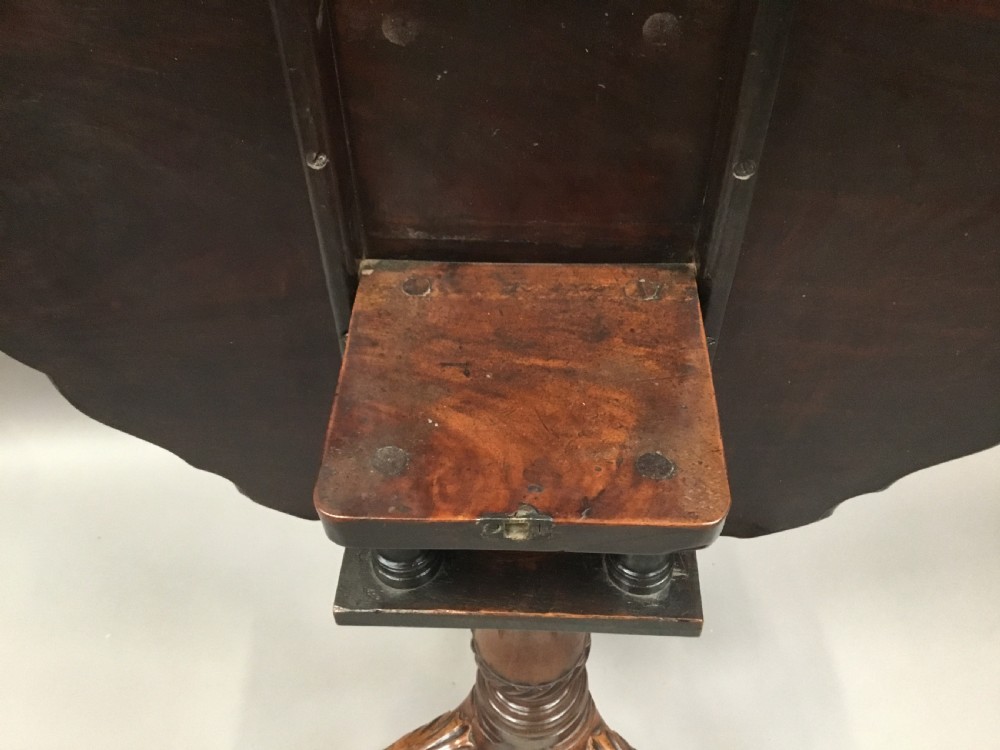 A mahogany George III style tripod table featuring a scalloped piecrust top, turned pedestal column, and cabriole legs with carved feet. View XIX