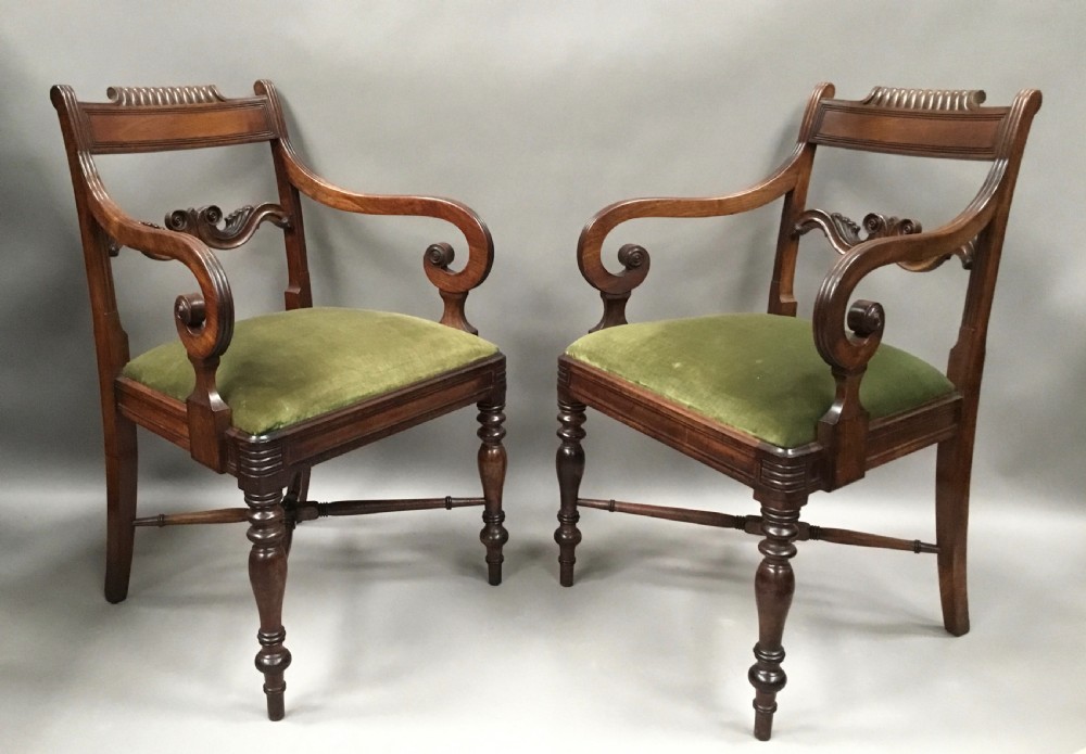 A pair of Regency mahogany open armchairs featuring scrolled armrests, turned front legs, and olive green velvet upholstered seats.