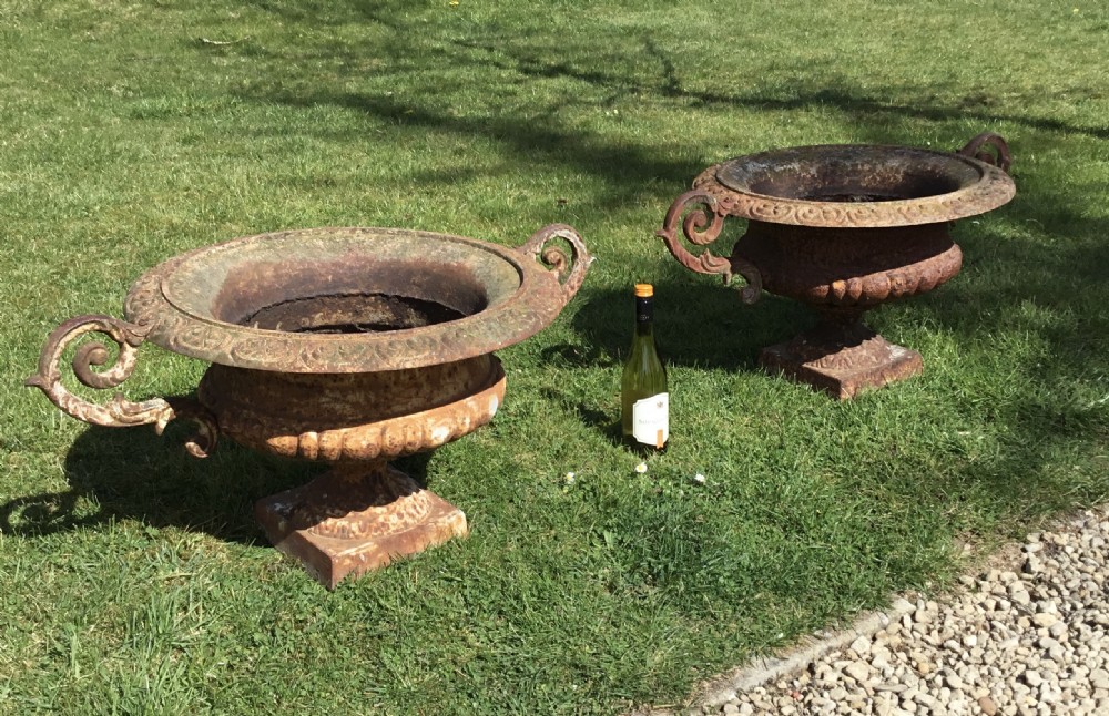 A pair of weathered 19th-century cast iron garden urns of shallow campana form with large scroll handles and square pedestal bases. View III