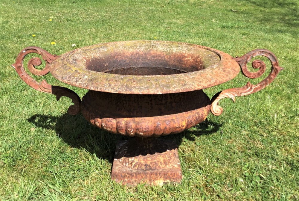 A pair of weathered 19th-century cast iron garden urns of shallow campana form with large scroll handles and square pedestal bases. View VI