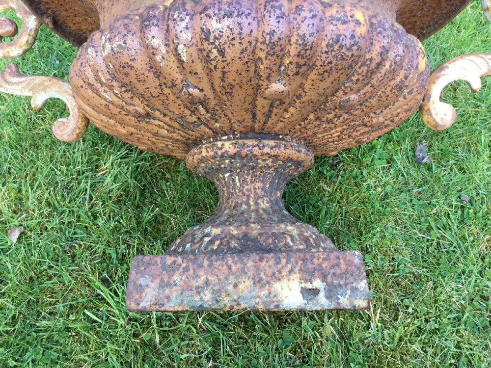 A pair of weathered 19th-century cast iron garden urns of shallow campana form with large scroll handles and square pedestal bases. View VIII