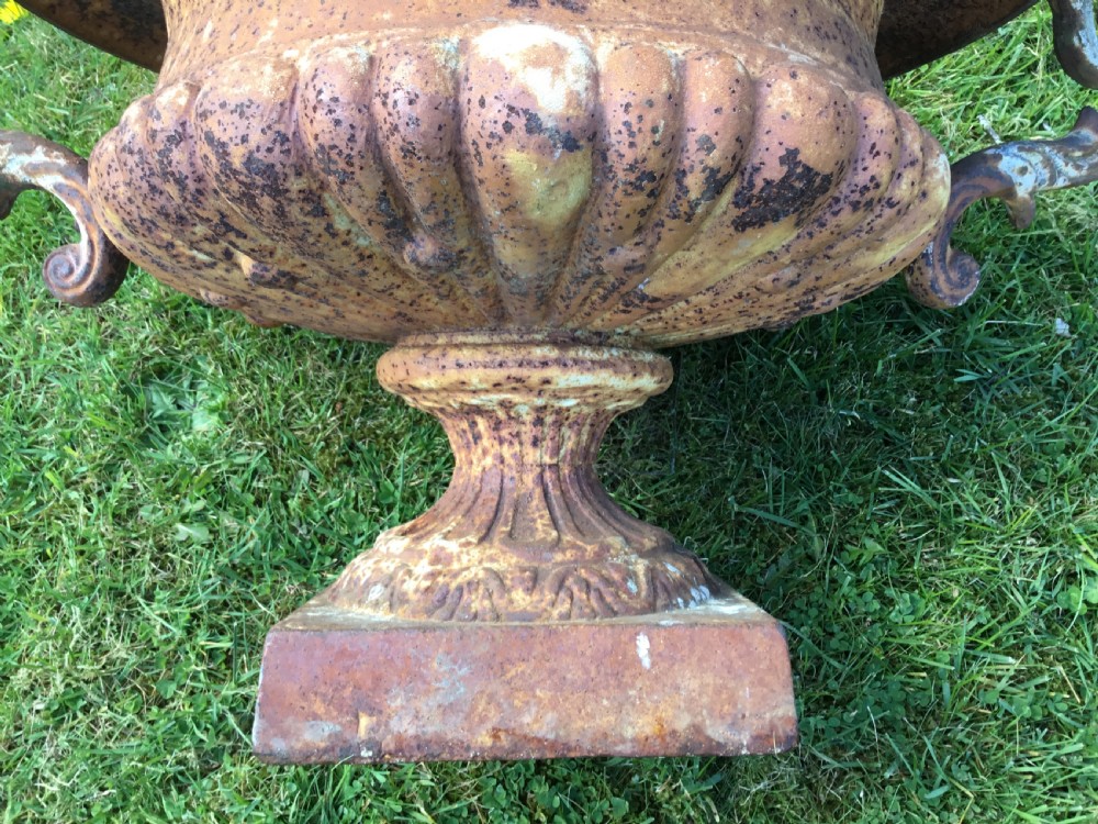 A pair of weathered 19th-century cast iron garden urns of shallow campana form with large scroll handles and square pedestal bases. View IX