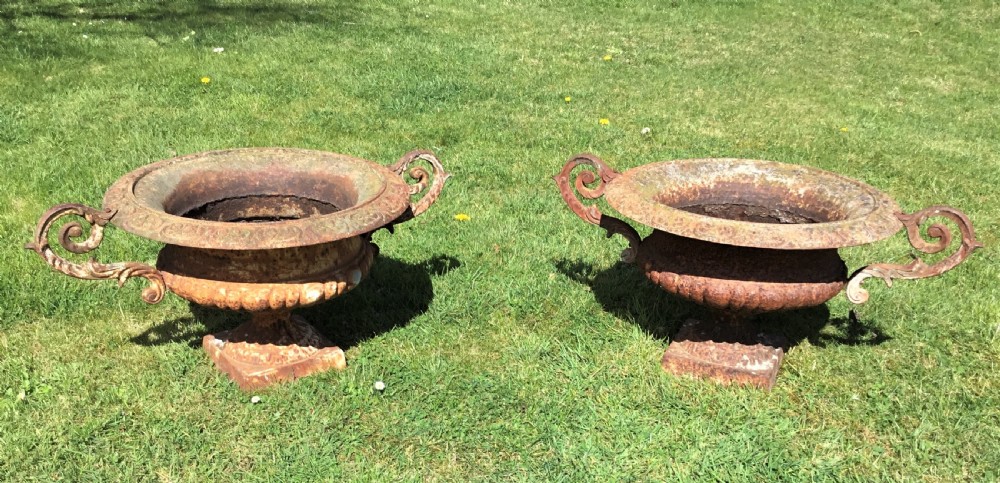 A pair of weathered 19th-century cast iron garden urns of shallow campana form with large scroll handles and square pedestal bases. View XIII