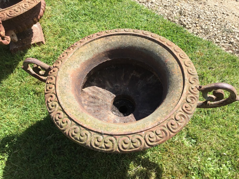 A pair of weathered 19th-century cast iron garden urns of shallow campana form with large scroll handles and square pedestal bases. View XV