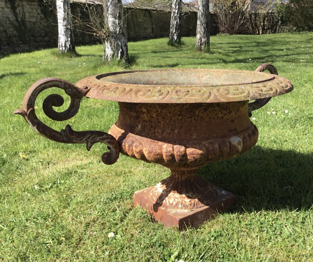 A pair of weathered 19th-century cast iron garden urns of shallow campana form with large scroll handles and square pedestal bases. View XVII