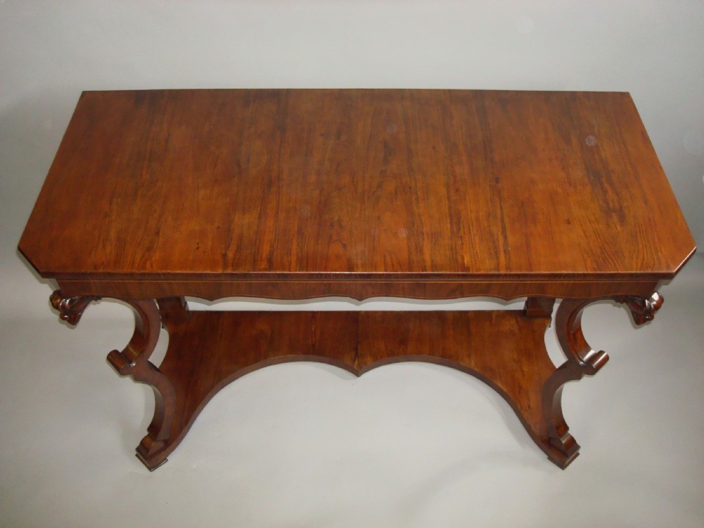 A pair of 19th-century Italian walnut console tables featuring carved zoomorphic legs, serpentine aprons with light string inlay, and lower curved stretchers. View IV