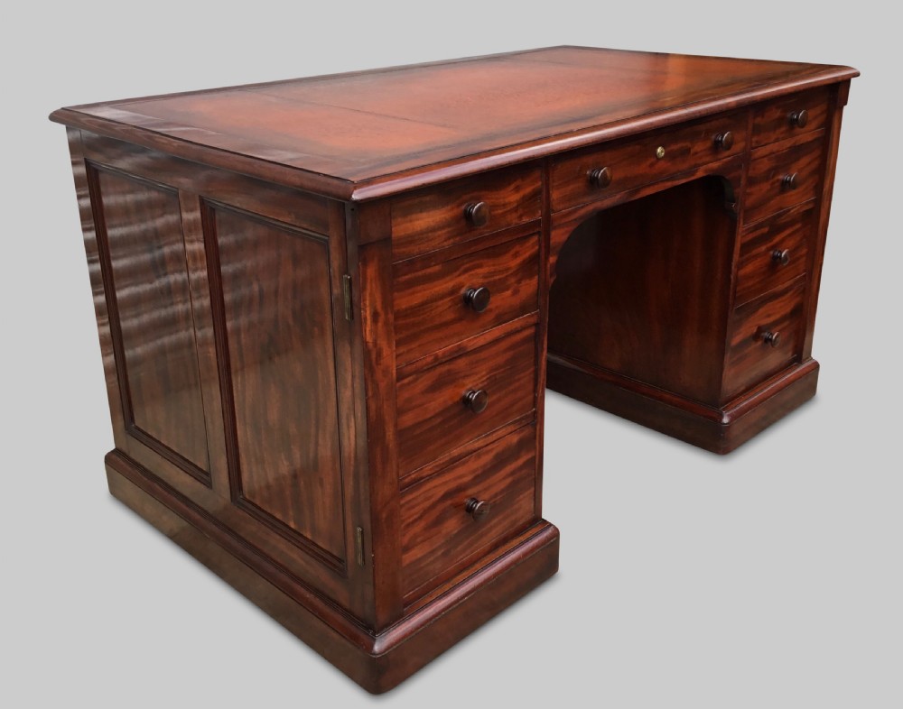 A Regency flame mahogany pedestal desk with an inset brown leather top, multiple drawers with turned wooden knobs, and twin panelled pedestals.