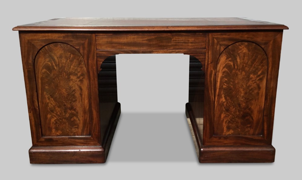 A Regency flame mahogany pedestal desk with an inset brown leather top, multiple drawers with turned wooden knobs, and twin panelled pedestals. View III