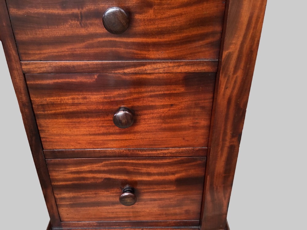 A Regency flame mahogany pedestal desk with an inset brown leather top, multiple drawers with turned wooden knobs, and twin panelled pedestals. View VII
