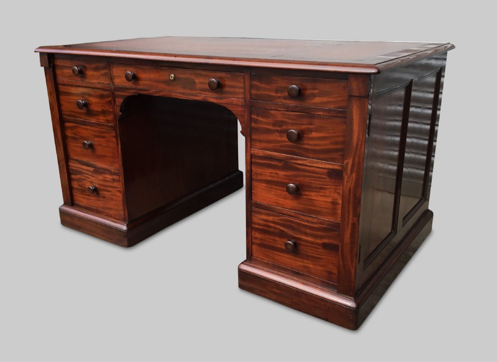 A Regency flame mahogany pedestal desk with an inset brown leather top, multiple drawers with turned wooden knobs, and twin panelled pedestals. View IX