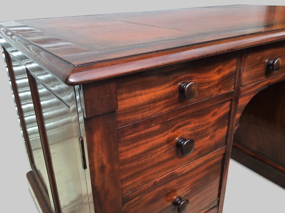 A Regency flame mahogany pedestal desk with an inset brown leather top, multiple drawers with turned wooden knobs, and twin panelled pedestals. View XI