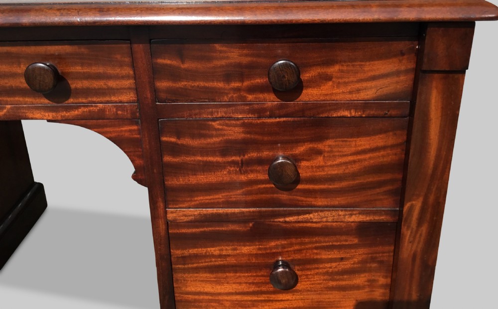 A Regency flame mahogany pedestal desk with an inset brown leather top, multiple drawers with turned wooden knobs, and twin panelled pedestals. View XV