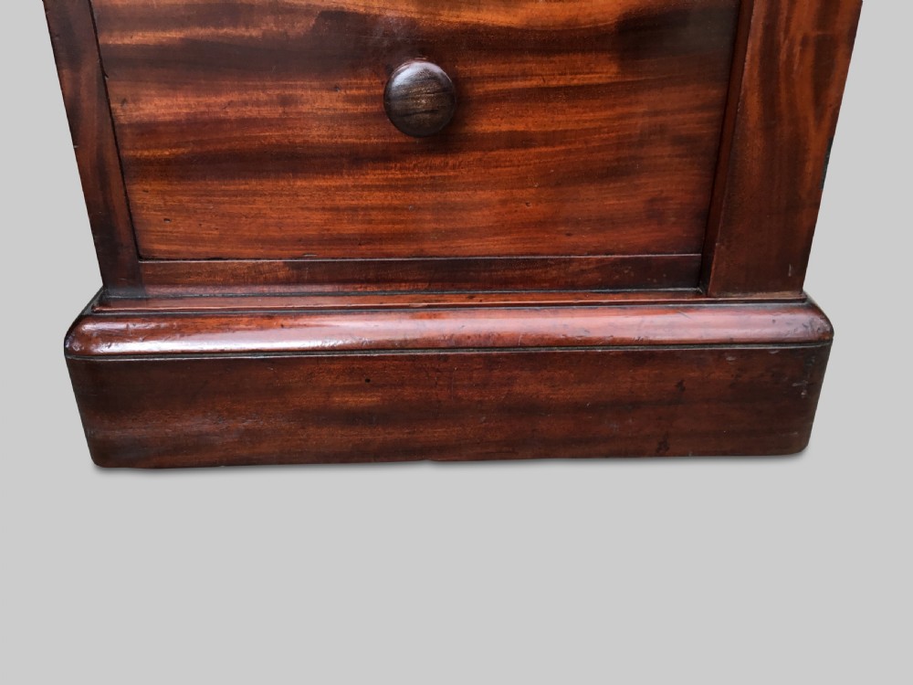 A Regency flame mahogany pedestal desk with an inset brown leather top, multiple drawers with turned wooden knobs, and twin panelled pedestals. View XVI