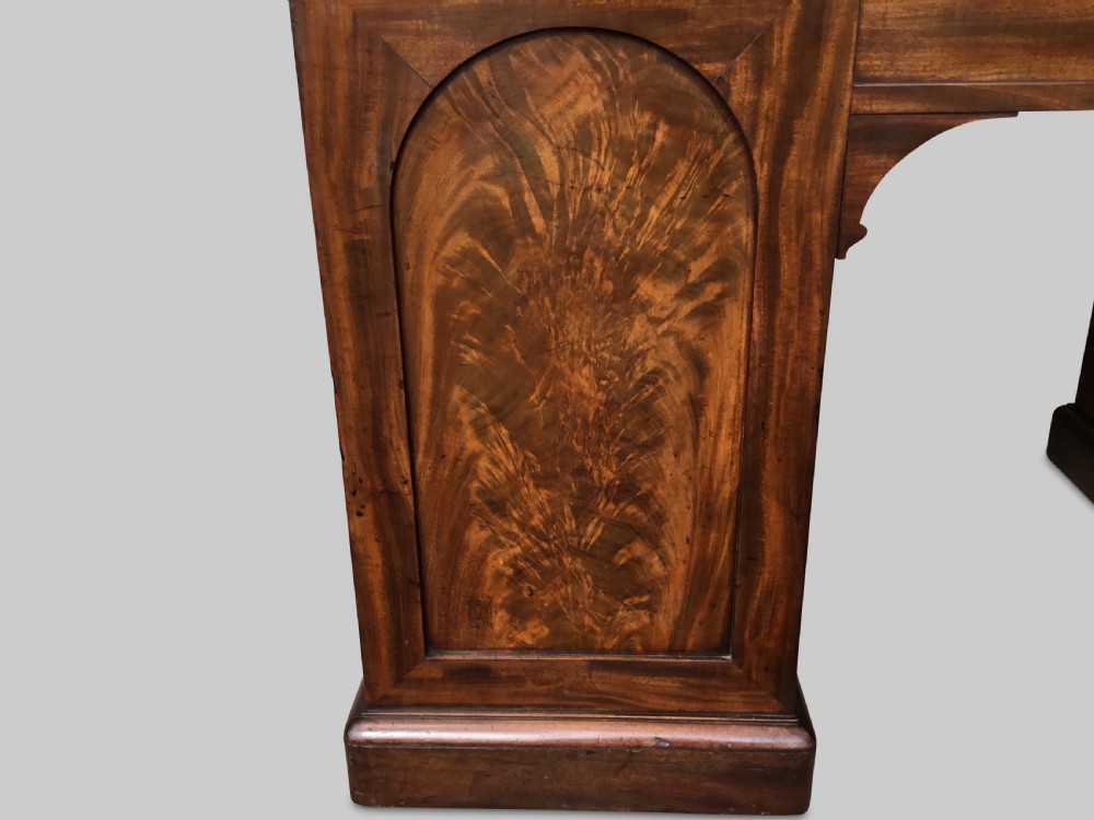 A Regency flame mahogany pedestal desk with an inset brown leather top, multiple drawers with turned wooden knobs, and twin panelled pedestals. View XIX