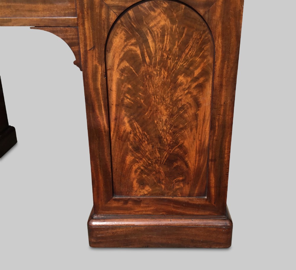 A Regency flame mahogany pedestal desk with an inset brown leather top, multiple drawers with turned wooden knobs, and twin panelled pedestals. View XX