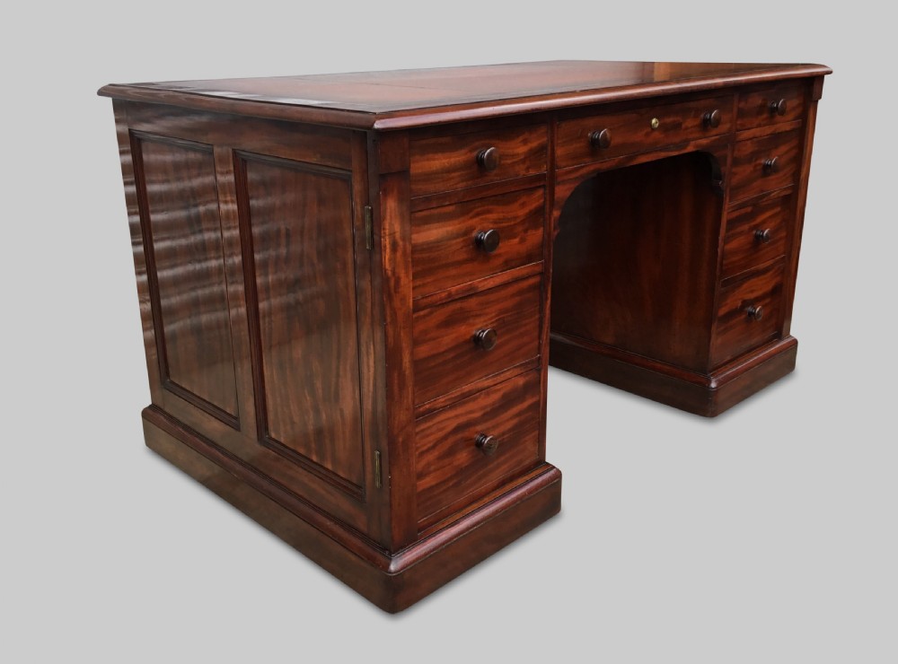 A Regency flame mahogany pedestal desk with an inset brown leather top, multiple drawers with turned wooden knobs, and twin panelled pedestals. View XXII