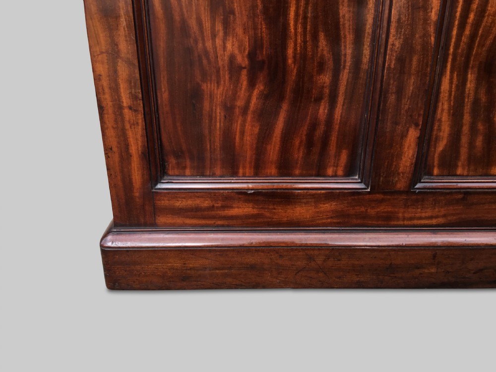 A Regency flame mahogany pedestal desk with an inset brown leather top, multiple drawers with turned wooden knobs, and twin panelled pedestals. View XXIII