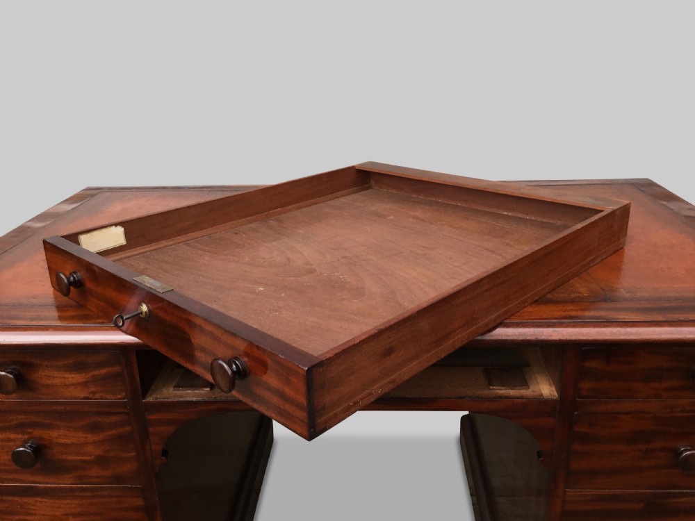 A Regency flame mahogany pedestal desk with an inset brown leather top, multiple drawers with turned wooden knobs, and twin panelled pedestals. View XXIV