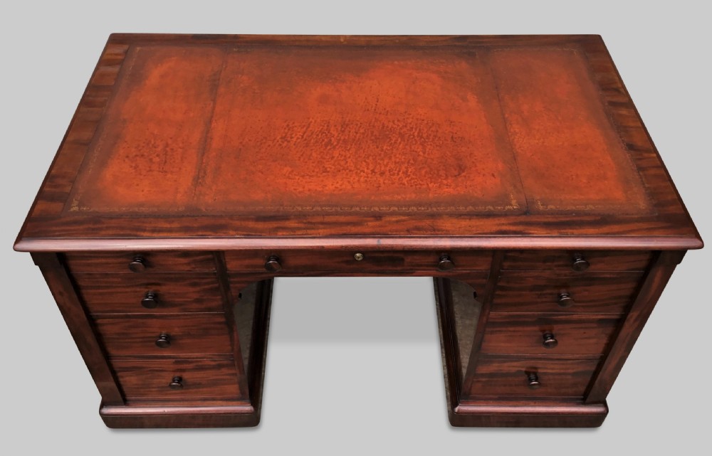 A Regency flame mahogany pedestal desk with an inset brown leather top, multiple drawers with turned wooden knobs, and twin panelled pedestals. View XXVIII