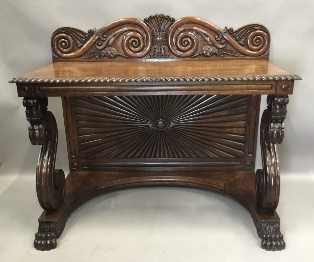 A 19th-century carved padouk console table featuring S-scroll legs, paw feet, a sunburst carved back panel, and a scrollwork gallery upstand. View II