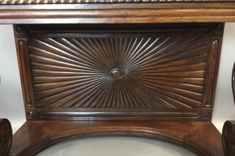 A 19th-century carved padouk console table featuring S-scroll legs, paw feet, a sunburst carved back panel, and a scrollwork gallery upstand. View IV