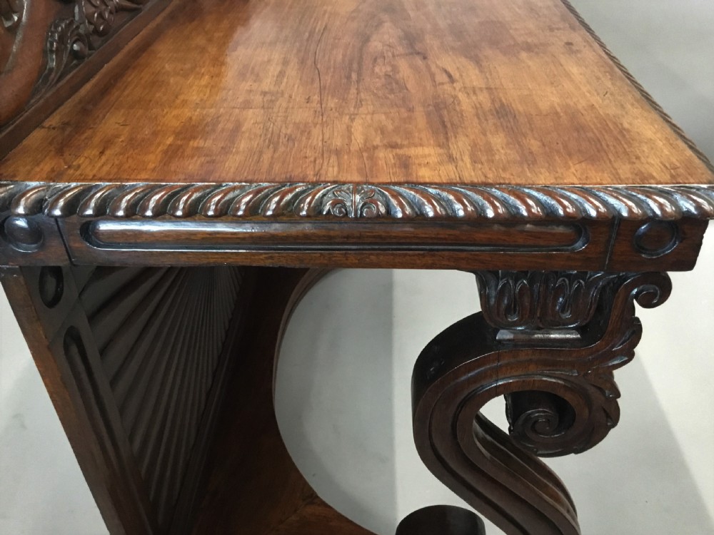 A 19th-century carved padouk console table featuring S-scroll legs, paw feet, a sunburst carved back panel, and a scrollwork gallery upstand. View VII