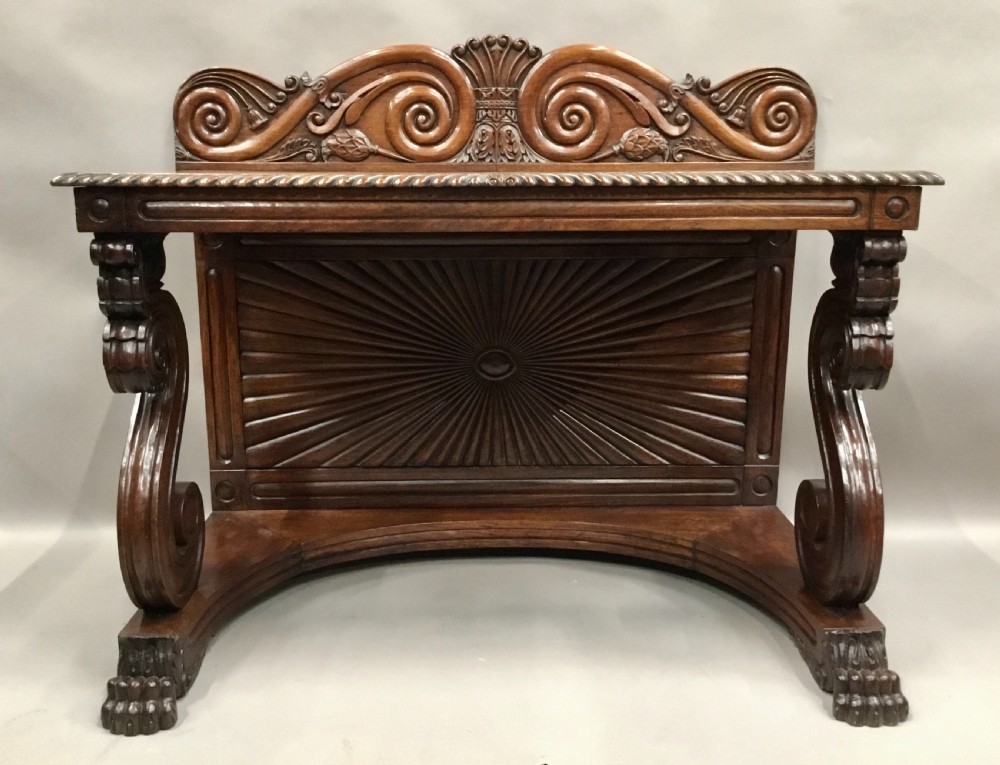 A 19th-century carved padouk console table featuring S-scroll legs, paw feet, a sunburst carved back panel, and a scrollwork gallery upstand. View VIII