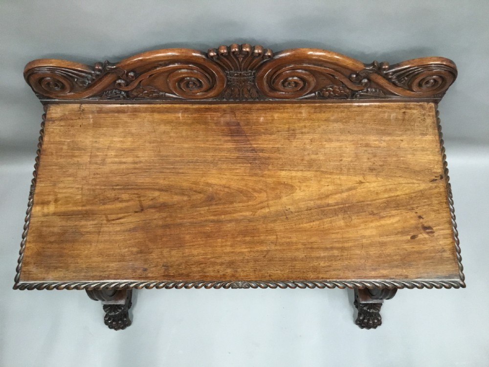 A 19th-century carved padouk console table featuring S-scroll legs, paw feet, a sunburst carved back panel, and a scrollwork gallery upstand. View X