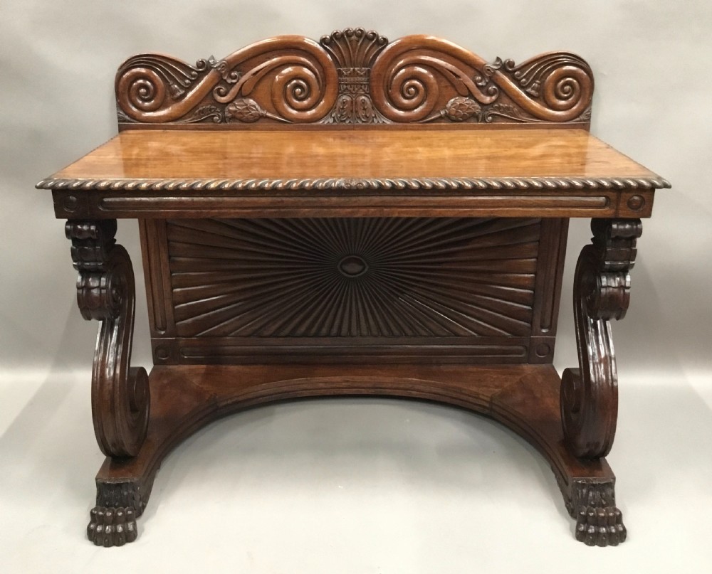 A 19th-century carved padouk console table featuring S-scroll legs, paw feet, a sunburst carved back panel, and a scrollwork gallery upstand. View XVIII