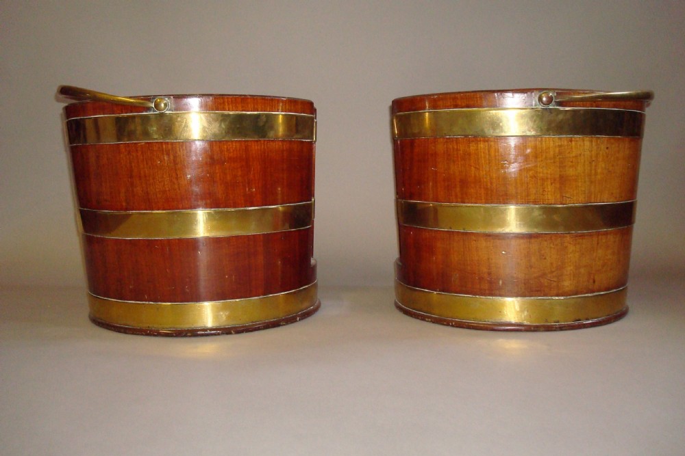 A pair of 18th-century mahogany plate buckets featuring brass binding straps, swing handles, and a vertical front cutout. View V