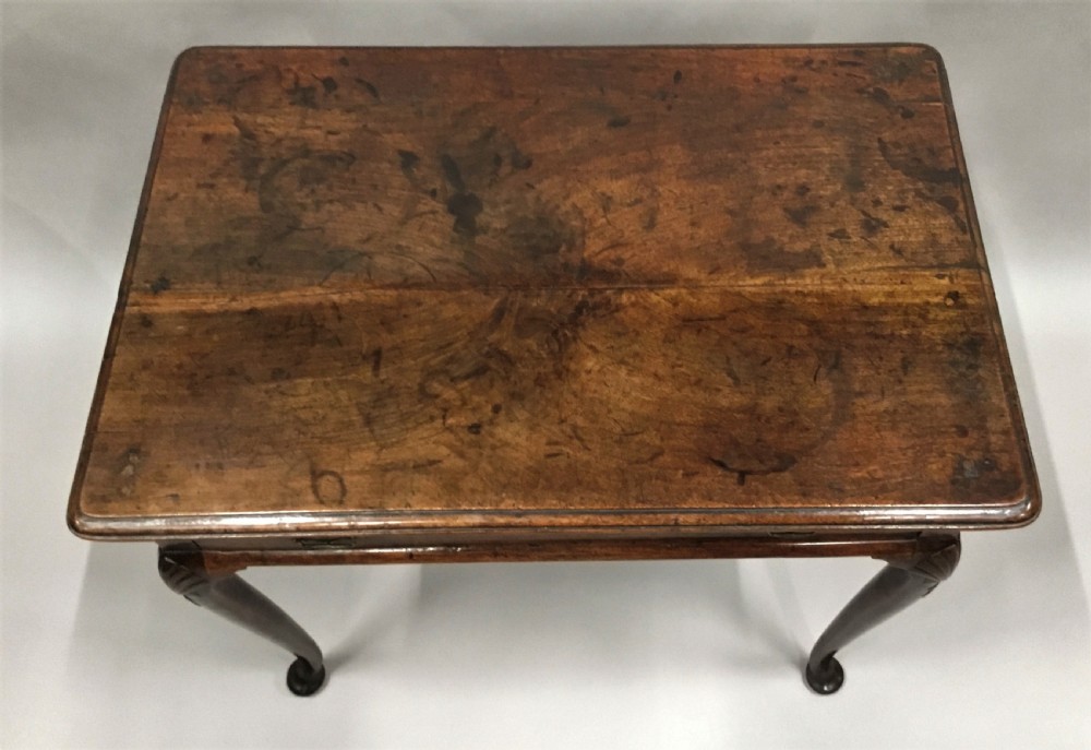 A George II dark walnut side table featuring carved shell knees on slender cabriole legs with pad feet and a single drawer with brass handles. View II