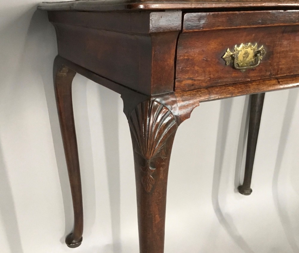 A George II dark walnut side table featuring carved shell knees on slender cabriole legs with pad feet and a single drawer with brass handles. View III