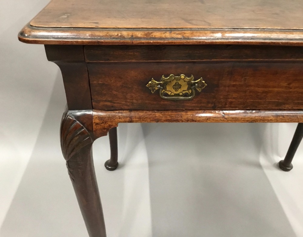 A George II dark walnut side table featuring carved shell knees on slender cabriole legs with pad feet and a single drawer with brass handles. View IX