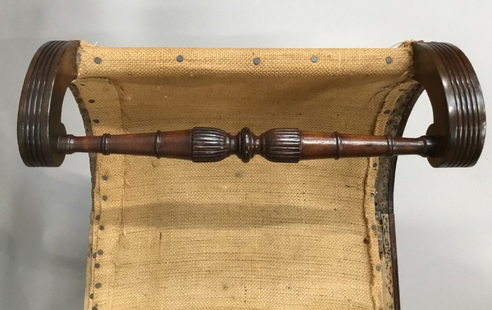 A Regency mahogany window seat with reeded scroll arms, turned legs on brass castors, and a calico-covered seat. View IV