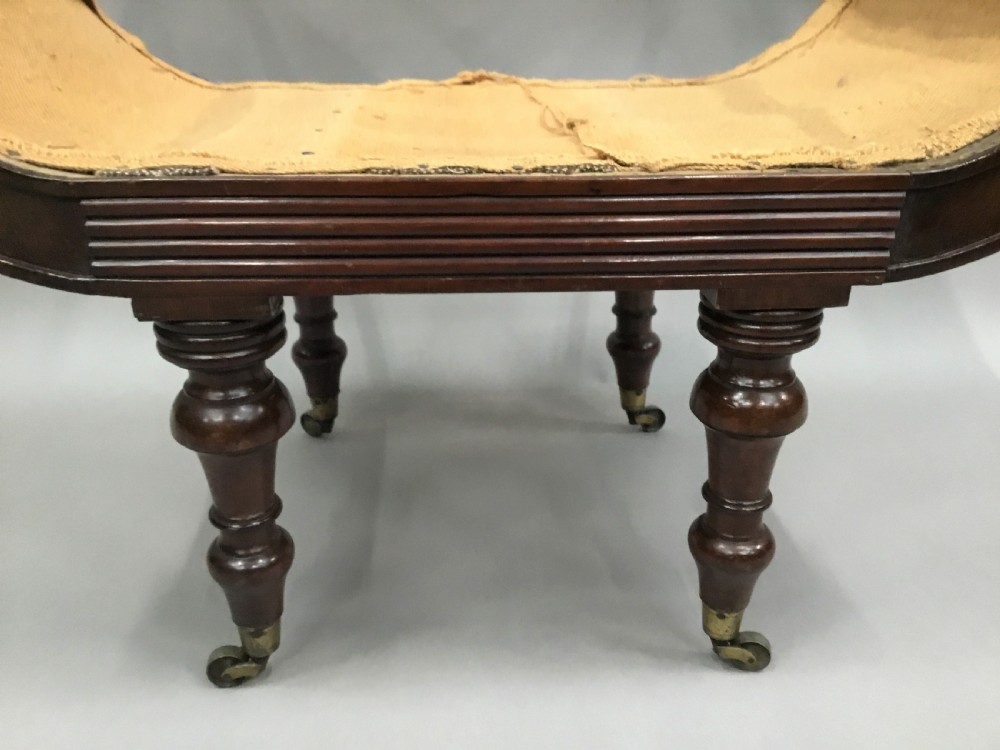 A Regency mahogany window seat with reeded scroll arms, turned legs on brass castors, and a calico-covered seat. View VI