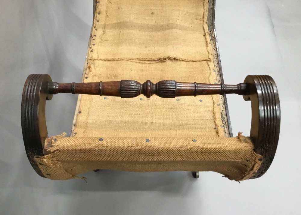 A Regency mahogany window seat with reeded scroll arms, turned legs on brass castors, and a calico-covered seat. View IX