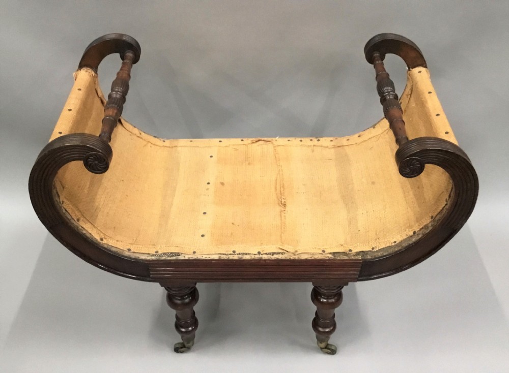 A Regency mahogany window seat with reeded scroll arms, turned legs on brass castors, and a calico-covered seat. View XIII