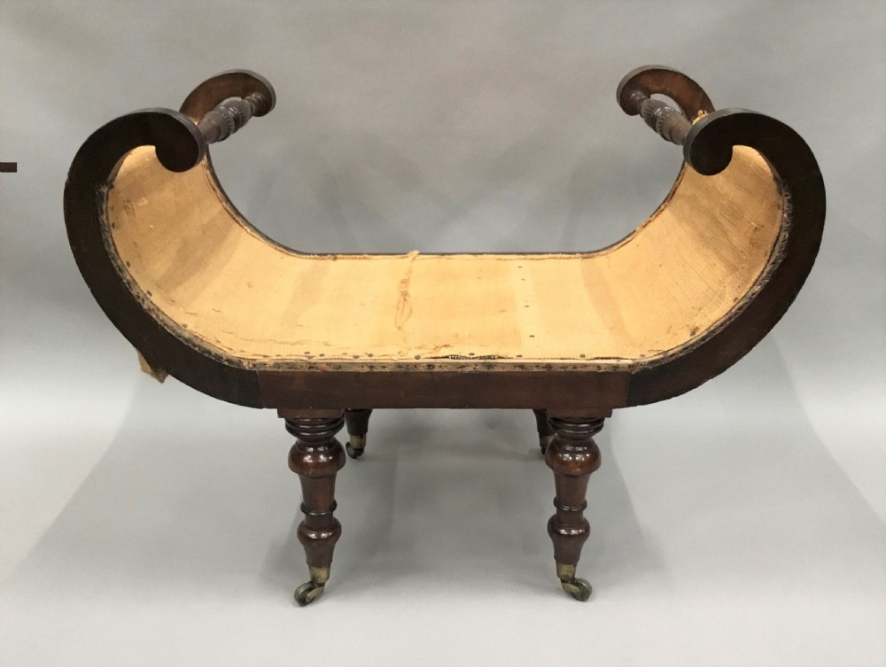 A Regency mahogany window seat with reeded scroll arms, turned legs on brass castors, and a calico-covered seat. View XVI