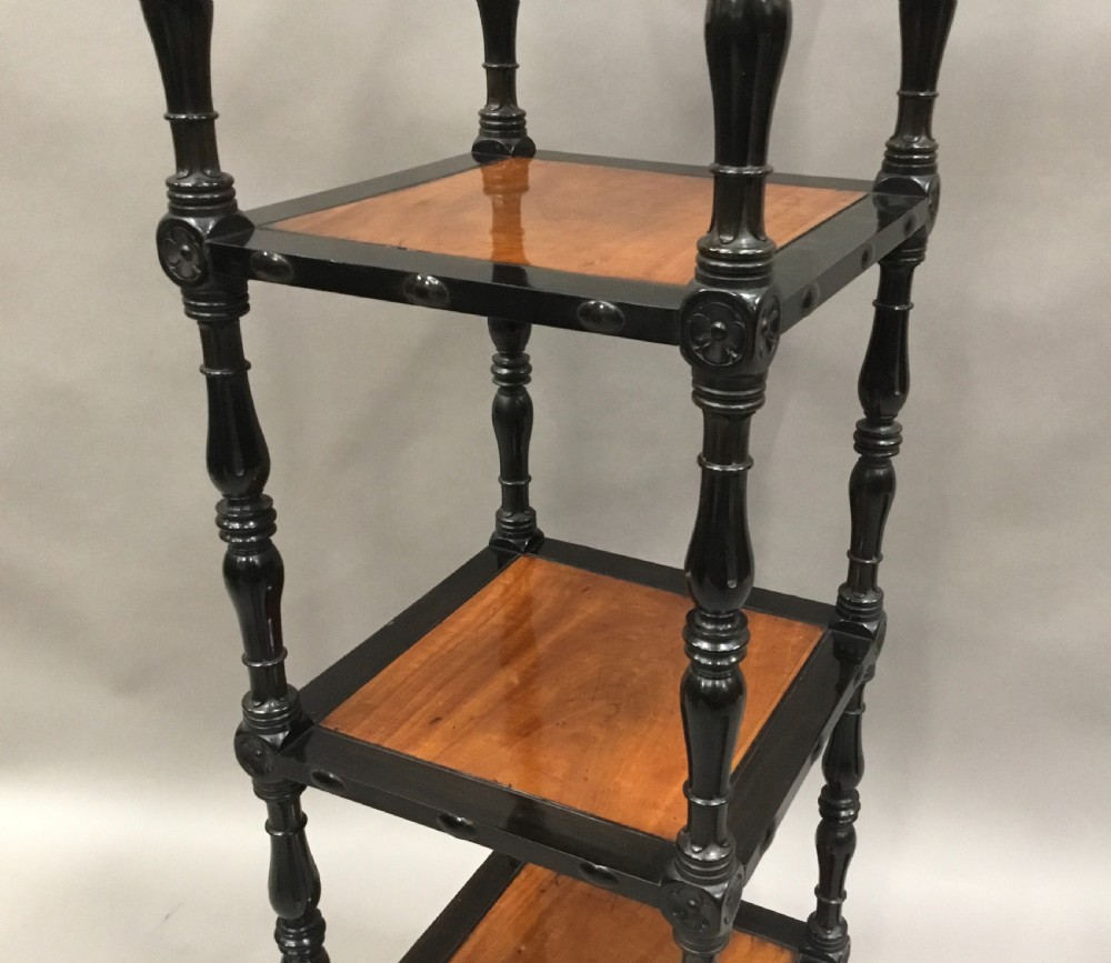 A four-tiered Ceylonese etagere featuring dark turned ebony supports and light satinwood shelf surfaces terminating in brass castors. View III