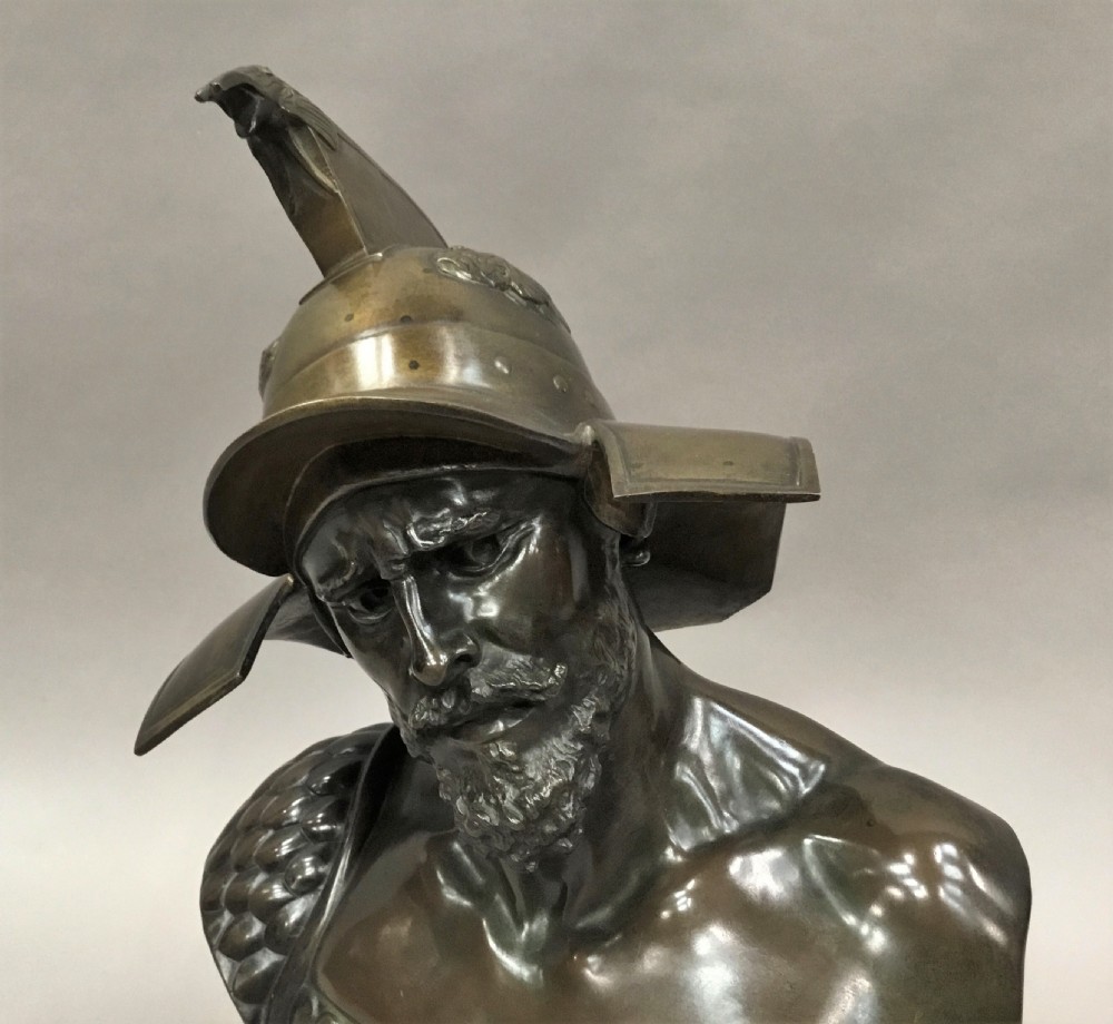 A 19th-century dark bronze bust depicting a helmeted Roman gladiator with a beard, mounted on a square variegated pink marble base. View XII