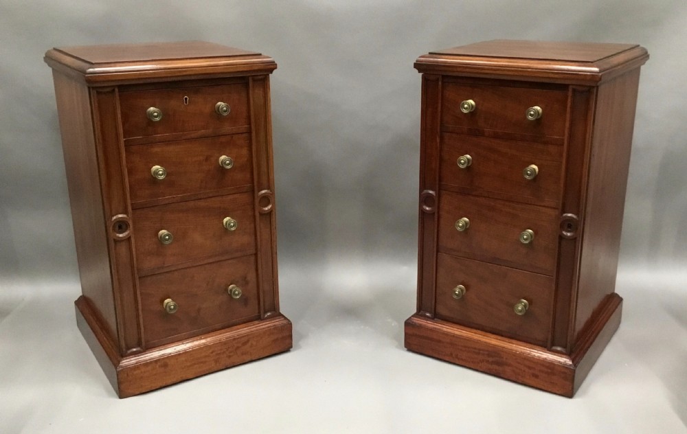 A pair of tall, narrow mahogany Wellington chests featuring four drawers each, turned brass knobs, and carved roundel pilasters on plinth bases. View II