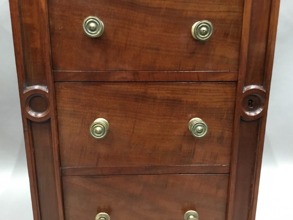 A pair of tall, narrow mahogany Wellington chests featuring four drawers each, turned brass knobs, and carved roundel pilasters on plinth bases. View XII