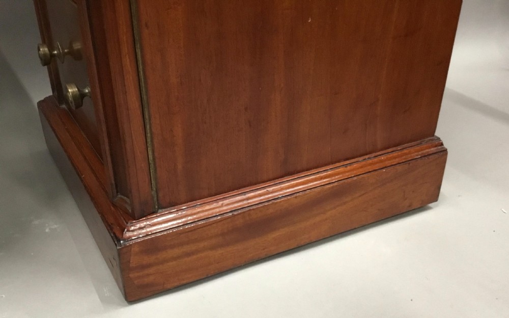 A pair of tall, narrow mahogany Wellington chests featuring four drawers each, turned brass knobs, and carved roundel pilasters on plinth bases. View XVIII