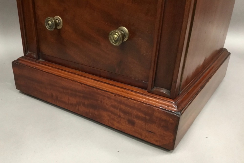 A pair of tall, narrow mahogany Wellington chests featuring four drawers each, turned brass knobs, and carved roundel pilasters on plinth bases. View XIX