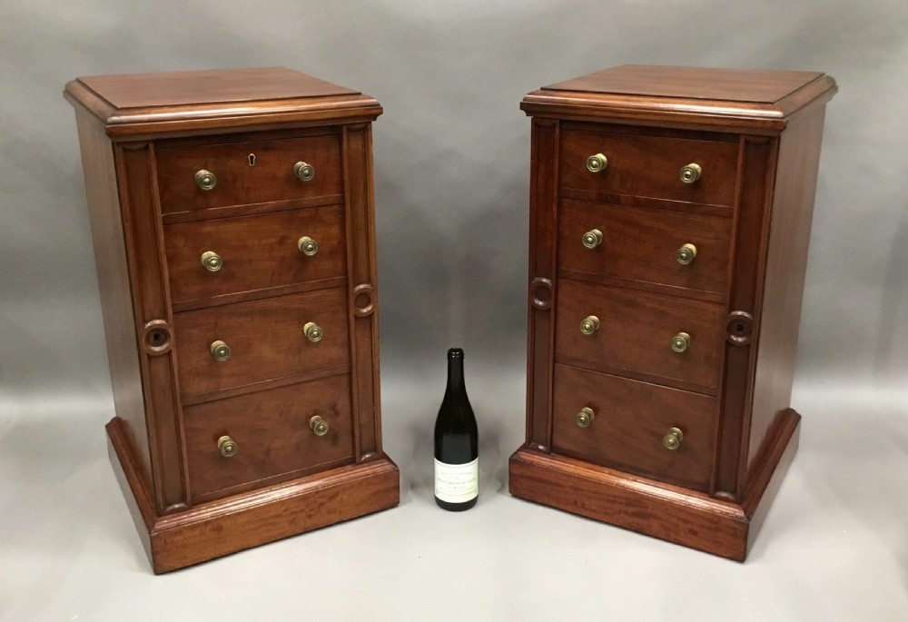 A pair of tall, narrow mahogany Wellington chests featuring four drawers each, turned brass knobs, and carved roundel pilasters on plinth bases. View XX
