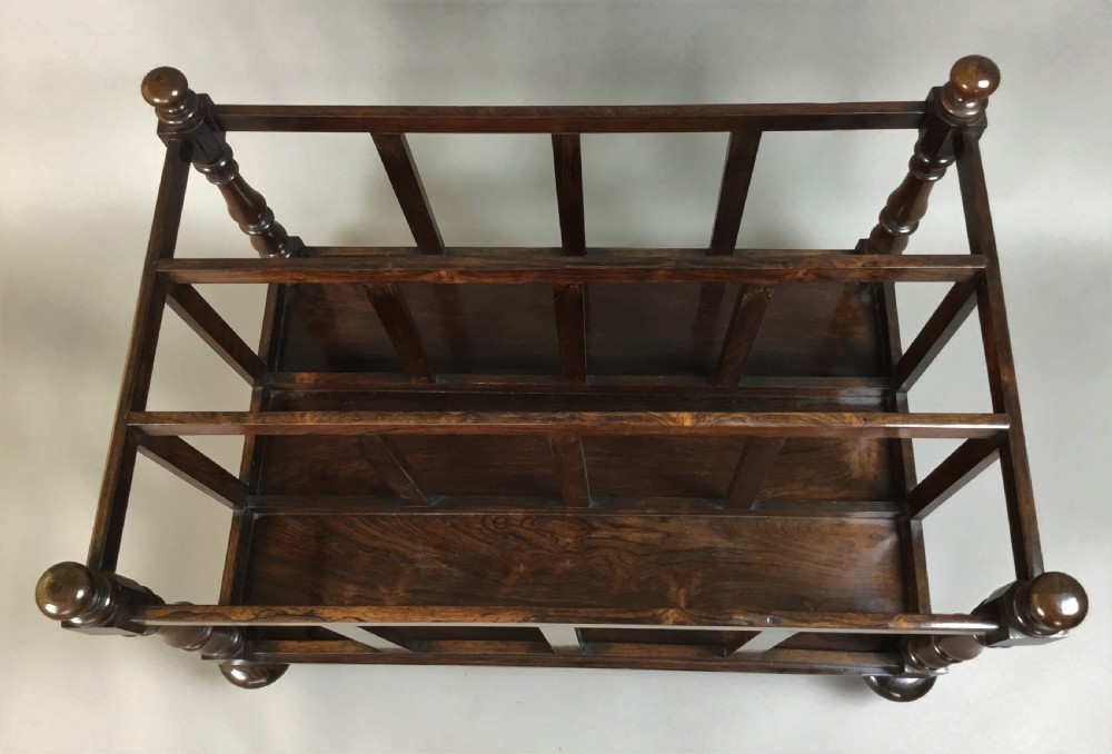 A dark rosewood Regency folio stand featuring slatted partitions, turned corner posts topped with finials, and brass wheel castors. View XIII